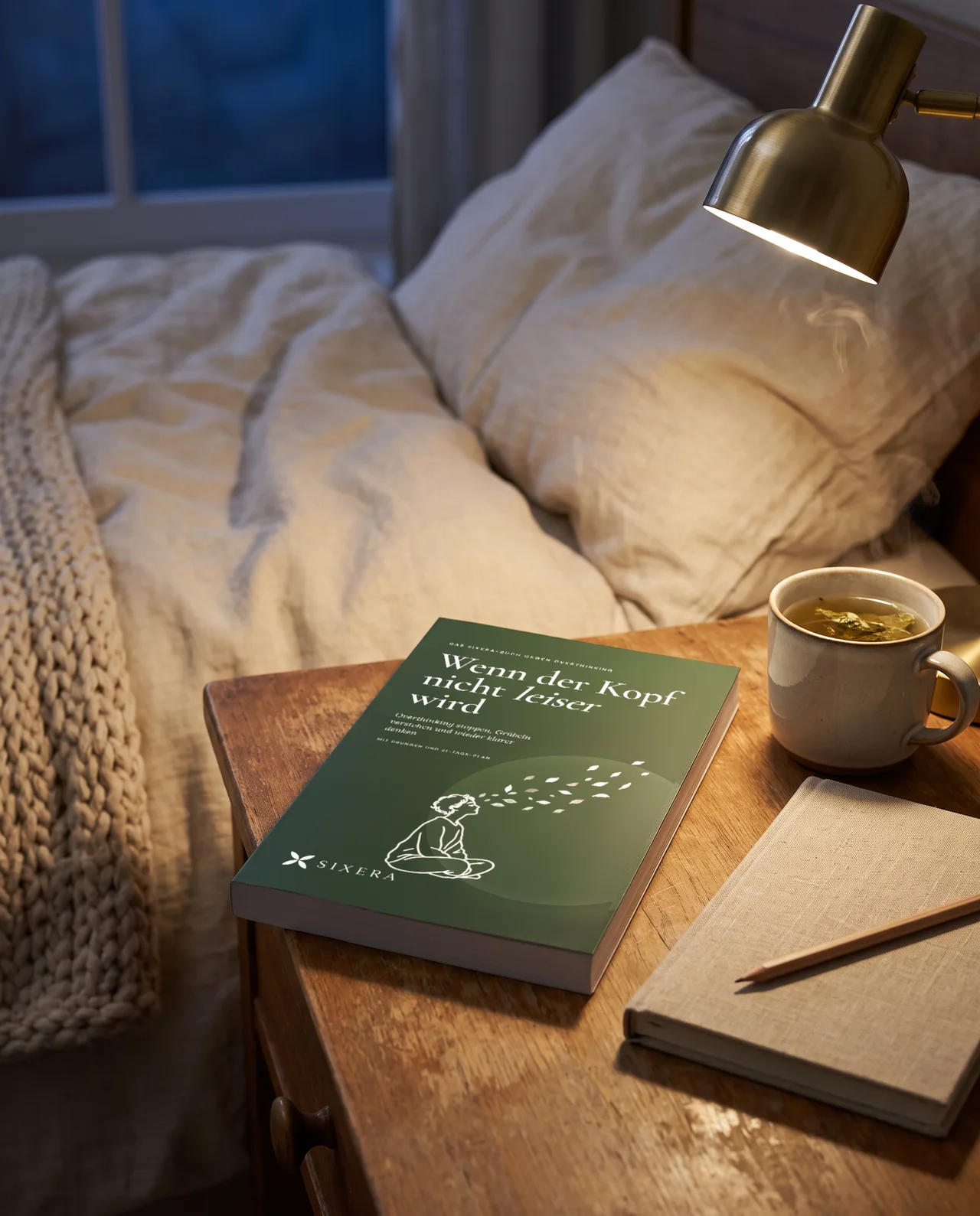Das Buch auf dem Nachttisch neben Tee und Leselampe